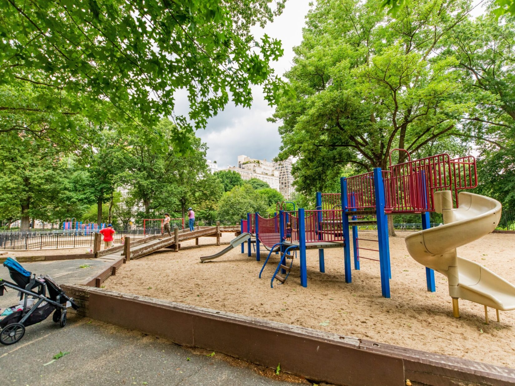 The climbing and sliding equipment in a large sandbox, seen in summer